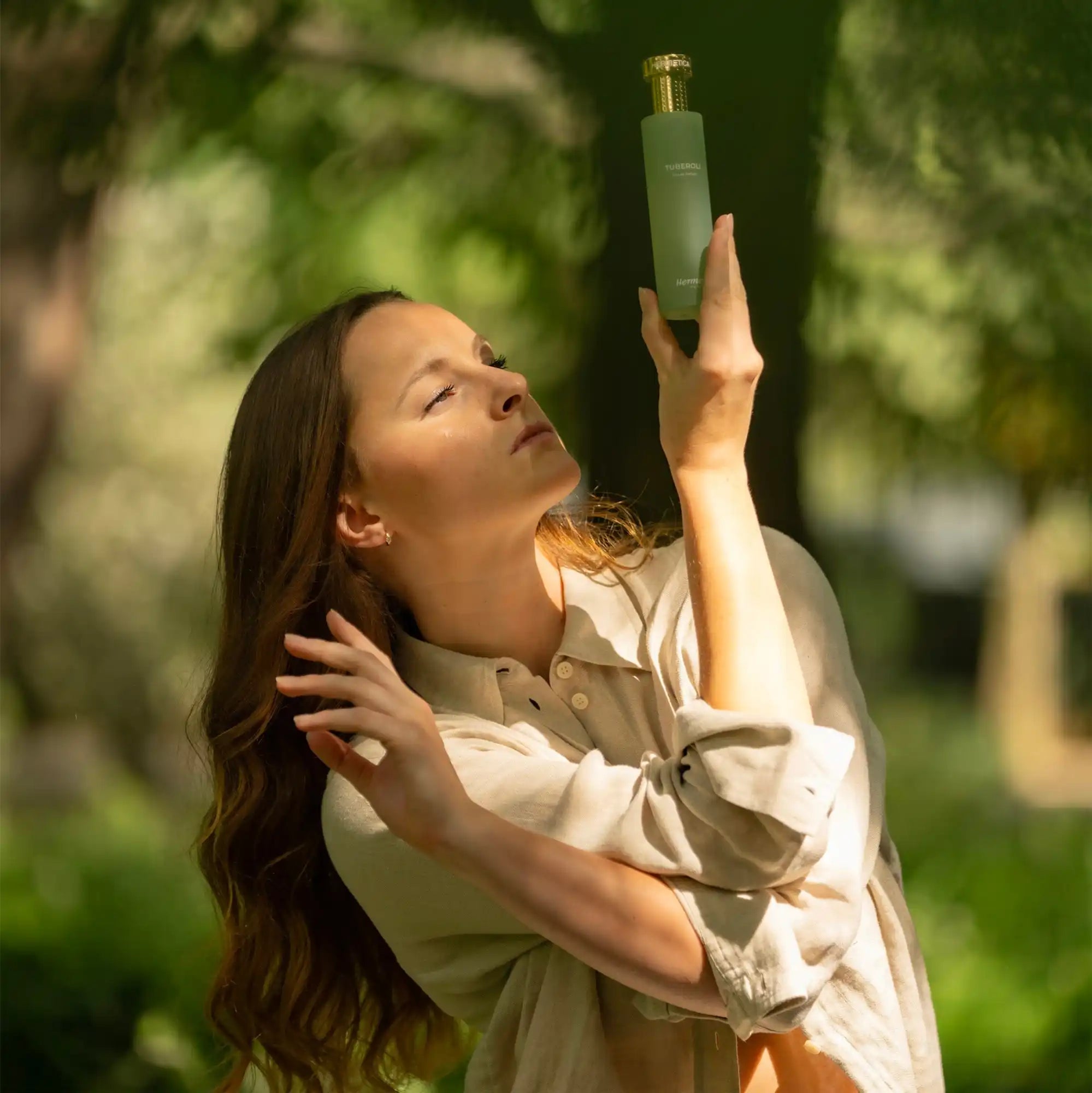 A green glass bottle being held up toward sunlight.