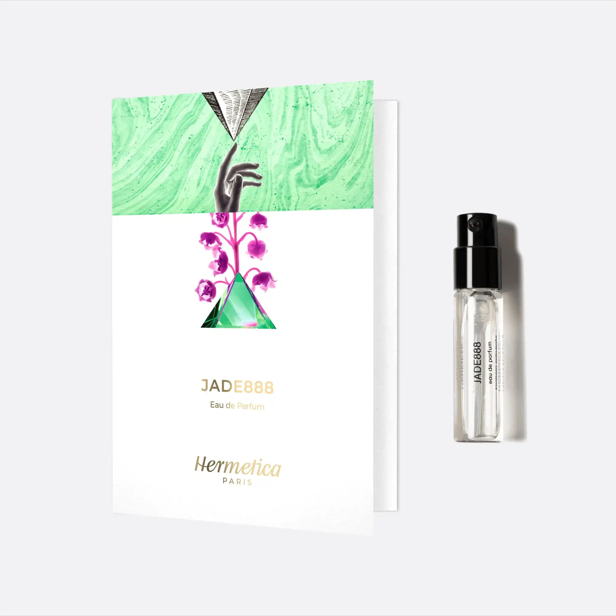 White card with green and pink floral artwork alongside a glass perfume vial.